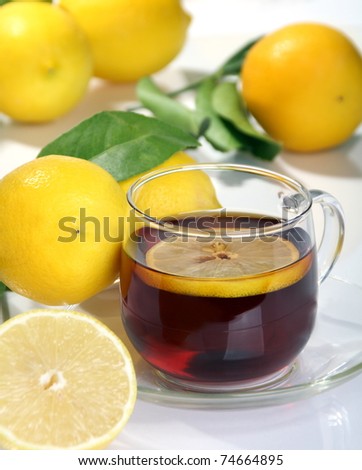 Tea with lemon in a glass bowl on a background of yellow lemons.