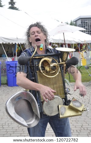 WINNIPEG, MB - JUNE 20:Street performer playing one man band instrument is entertaining the children for the Kids Fest 2012 at the Forks. June 20, 2012 in Winnipeg, Manitoba
