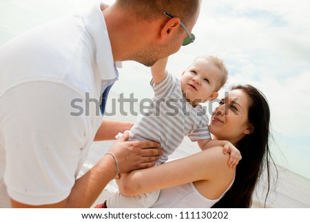 Happy young parents with child against the sea