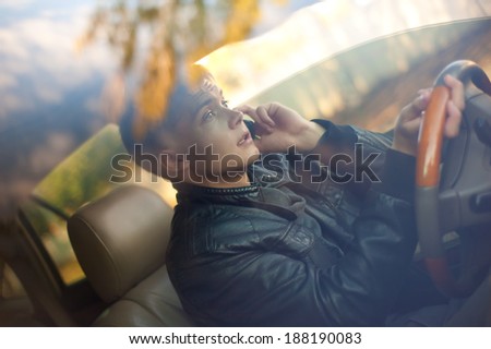 Handsome guy in the car looks at the road and talking by phone