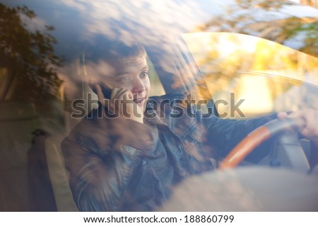 Handsome guy in the car looks at the road and talking by phone