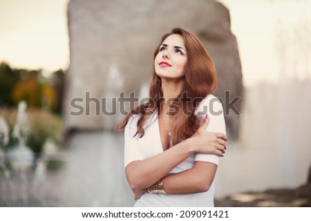 beautiful woman hugging herself near the fountain