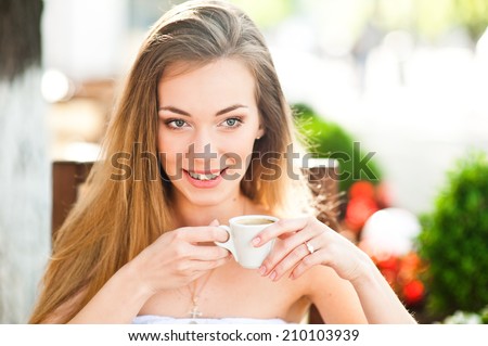 Pretty woman with cup of coffee looks into the distance