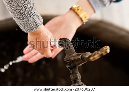 Woman\'s hand and the hand of child catching a jet of water under the tap