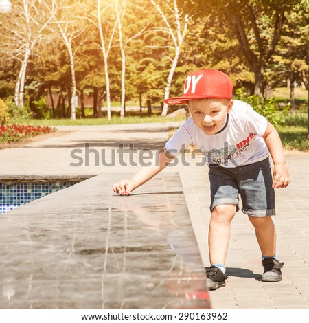 Little boy playing outdoors in the city in park, wheels toy car on a marble surface