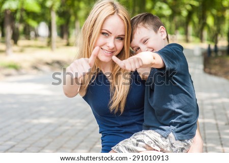 Mother and son together outdoors show thumb and say that everything is fine