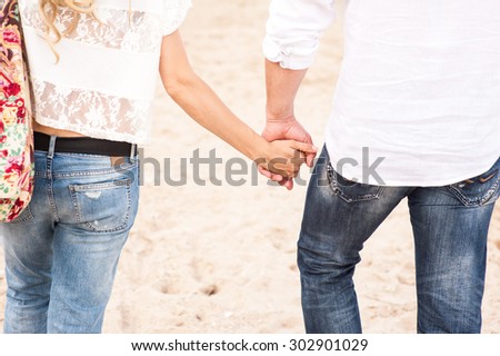 Woman and man holding hands walking on the beach