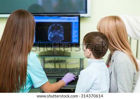Meeting child and mother with doctor at specialized children\'s hospital and showing health of the patient on the screen