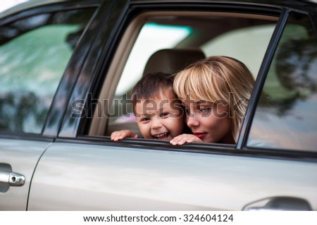 Beautiful woman with a child four years in the car are going to have a trip