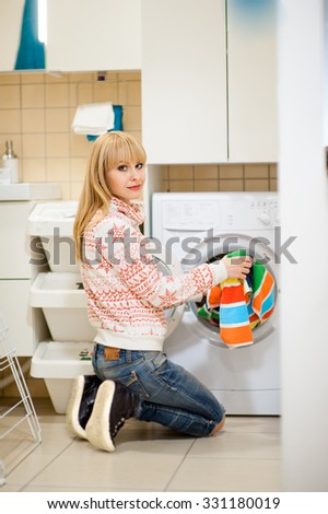 Housekeeper of 25 years old loads things in the washing machine in the bathroom