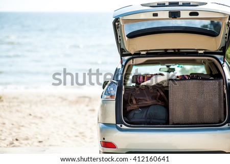Big luggage, suitcase, bag inside the trunk of cream, silver car jeep on the beach