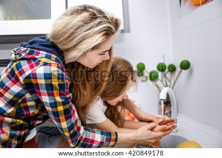 Beautiful young woman with a baby wash dishes at the kitchen