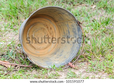 Dirty metal bucket on the ground of paddy field.