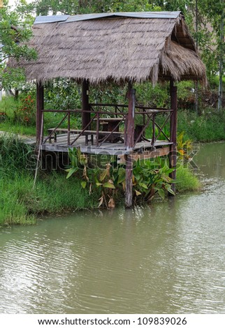 Wooden hut of country restaurant near the clear pond.