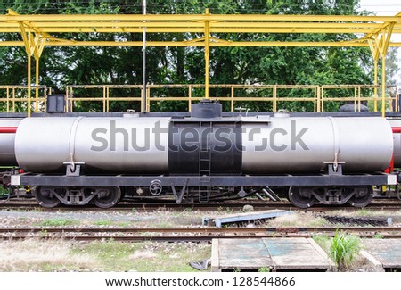 Modern gas tanker in freight train at station.