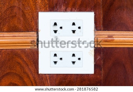 Dirty white outlet on the wooden wall of living room.