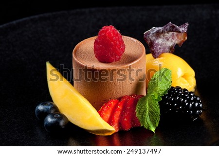 Dessert chocolate mousse cake with fruits and berries isolated on black