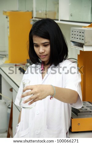 Female scientist looking at beaker seriously