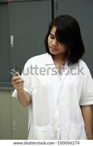 Female scientist looking at beaker seriously