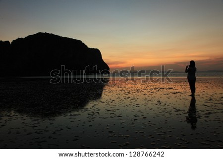 Silhouette of young woman, standing alone by the sea