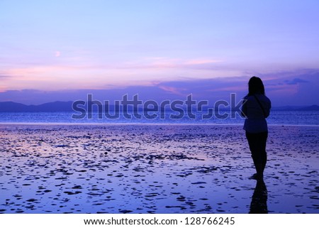 Silhouette of young woman, standing alone by the sea