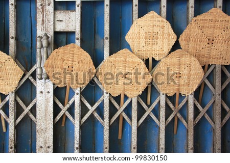 traditional weaved fan, handmade work from bamboo. Thai handcraft against rusty shutter door