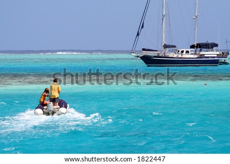 two persons on an inflatable tender, approaching the yacht