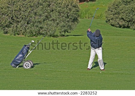 golfer at top of swing on a golf course