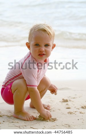stock photo baby girl squatting down on a beach
