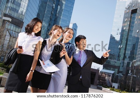 Happy diverse group of executives pointing over business center. Outdoor