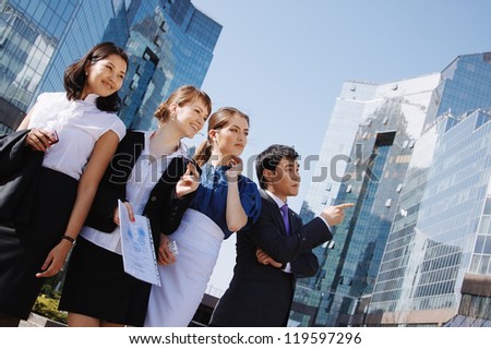 Happy diverse group of executives pointing over business center. Outdoor