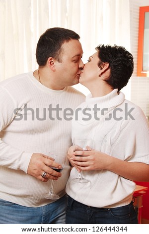Family in home kitchen drinking wine. Kissing couple
