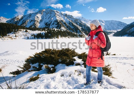 Young woman take a walk on winter mountain slope (Big Almaty Lake, Kazakhstan)