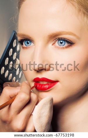 Portrait of a woman putting on lip liner.