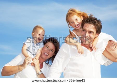 young happy family having fun outdoors, dressed in white and with blue sky in background