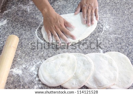 Human hands kneading bread dough for pizza