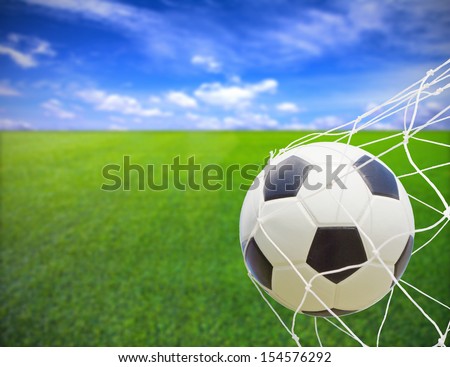 soccer ball in goal net over blue sky background