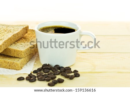 Delicious breakfast with toast, white cup coffee with coffee beans on wood table