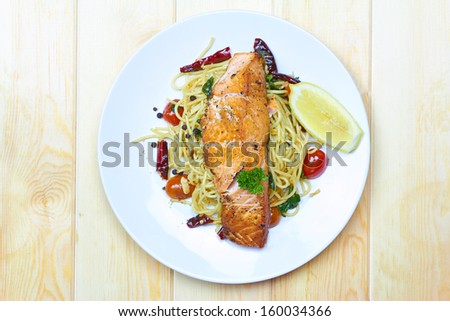 Spaghetti Salmon with chilli, tomato on white plate over wood background, View top