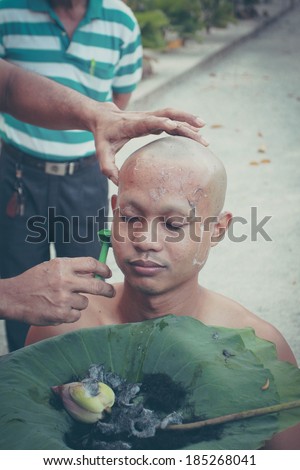 PHANGNGA,THAILAND FEBRUARY 08 :Thai man gets his head shaved by a monk during a Buddhist ordination ceremony on February 08, 2014 in Phangnga Thailand.