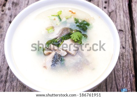 bowl of fish and wild rice soup with vegetables on wood table