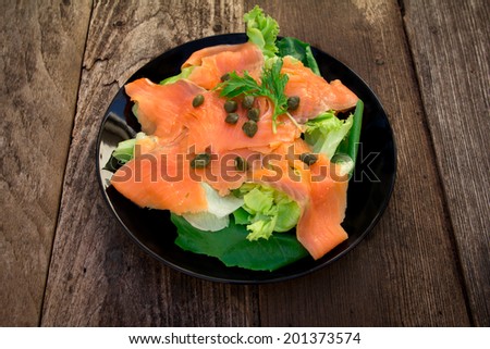 Smoked salmon with salad leaves on old wood.