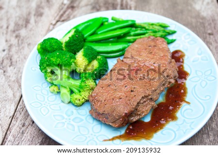 grilled fillet steak served with boiled vegetables on an old wooden board