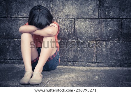 sad and depressed little Asian girl sitting in grunge room, filtered images
