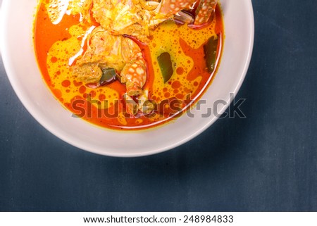 Spicy coconut milk soup with crab on wood, top view