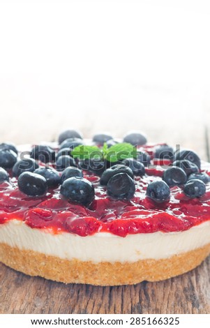 Strawberry cheese pie with fresh blueberry on wood