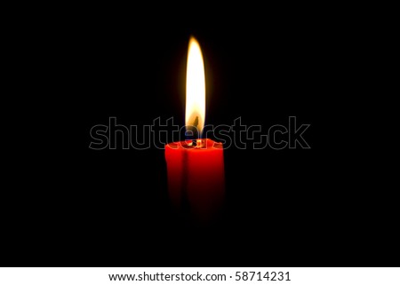 Closeup of burning red candle isolated on black background