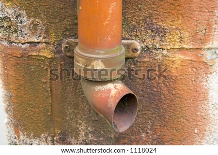 A deep rusty red textured photograph of a back street gutter pipe.