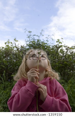 stock photo Young school girl blowing dandelion seeds