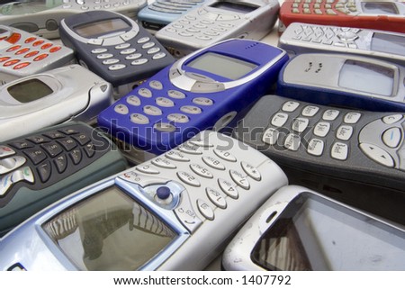 Scattered old mobile phone handsets. All makes and models in various states of disrepair.